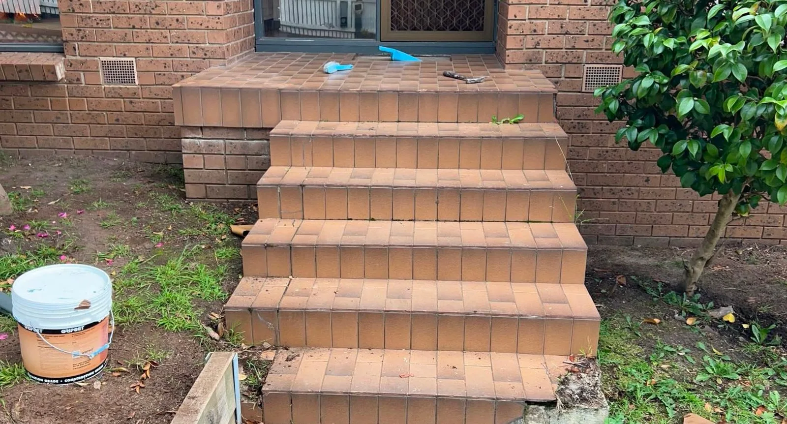 Front steps before — worn terracotta-brown step tiles